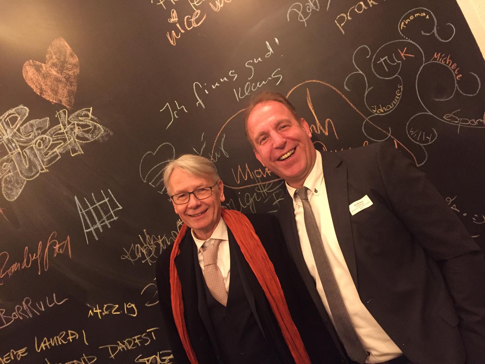 Zwei Männer (Oberbürgermeister Dr. Klaus Weichel und Staatssekretär Randolf Stich) stehen vor einer Kreidetafel nebeneinander.