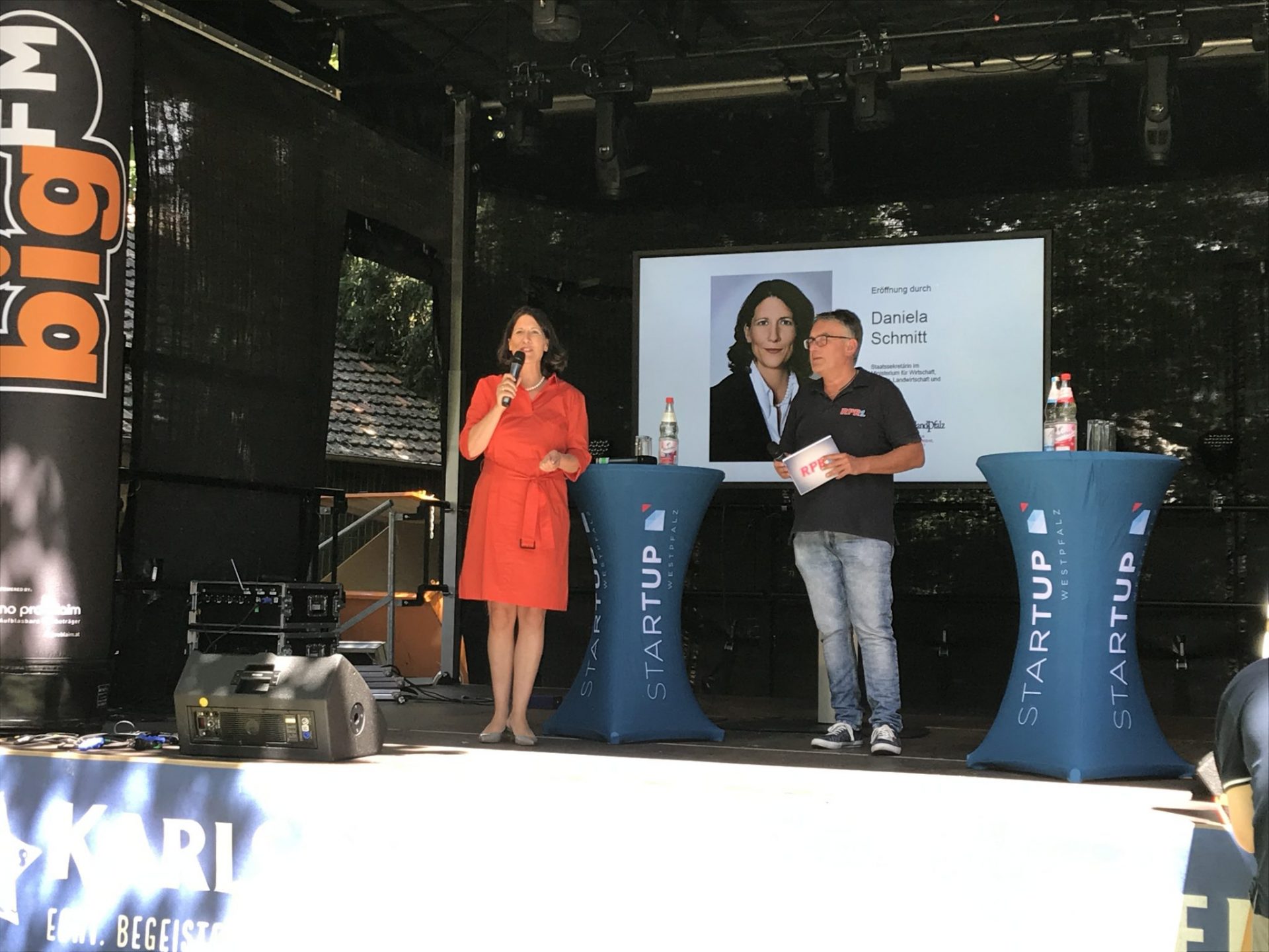 Staatssekretärin Daniela Schmitt eröffnet das Startup Festival. Dafür steht sie neben einem Moderator auf einer Bühne.