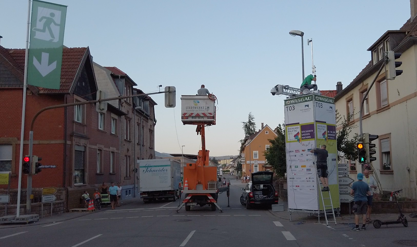 Eine Hebebühne steht in Annweiler auf einer Straße, Männer verlegen Kabel und bauen Masten auf.