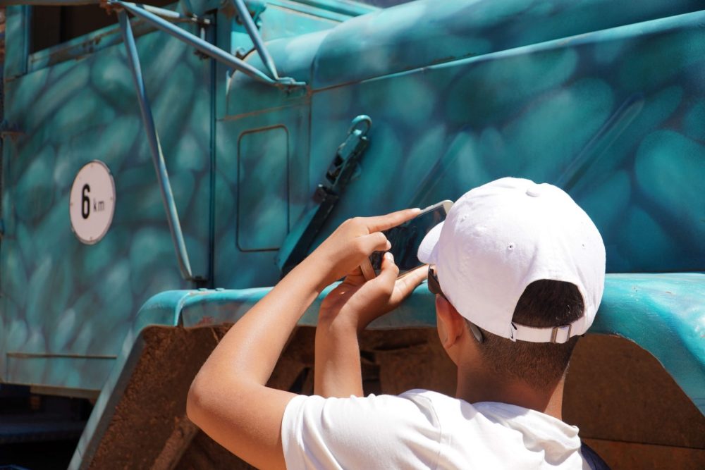Ein Junge fotografiert einen LKW mit seinem Handy.