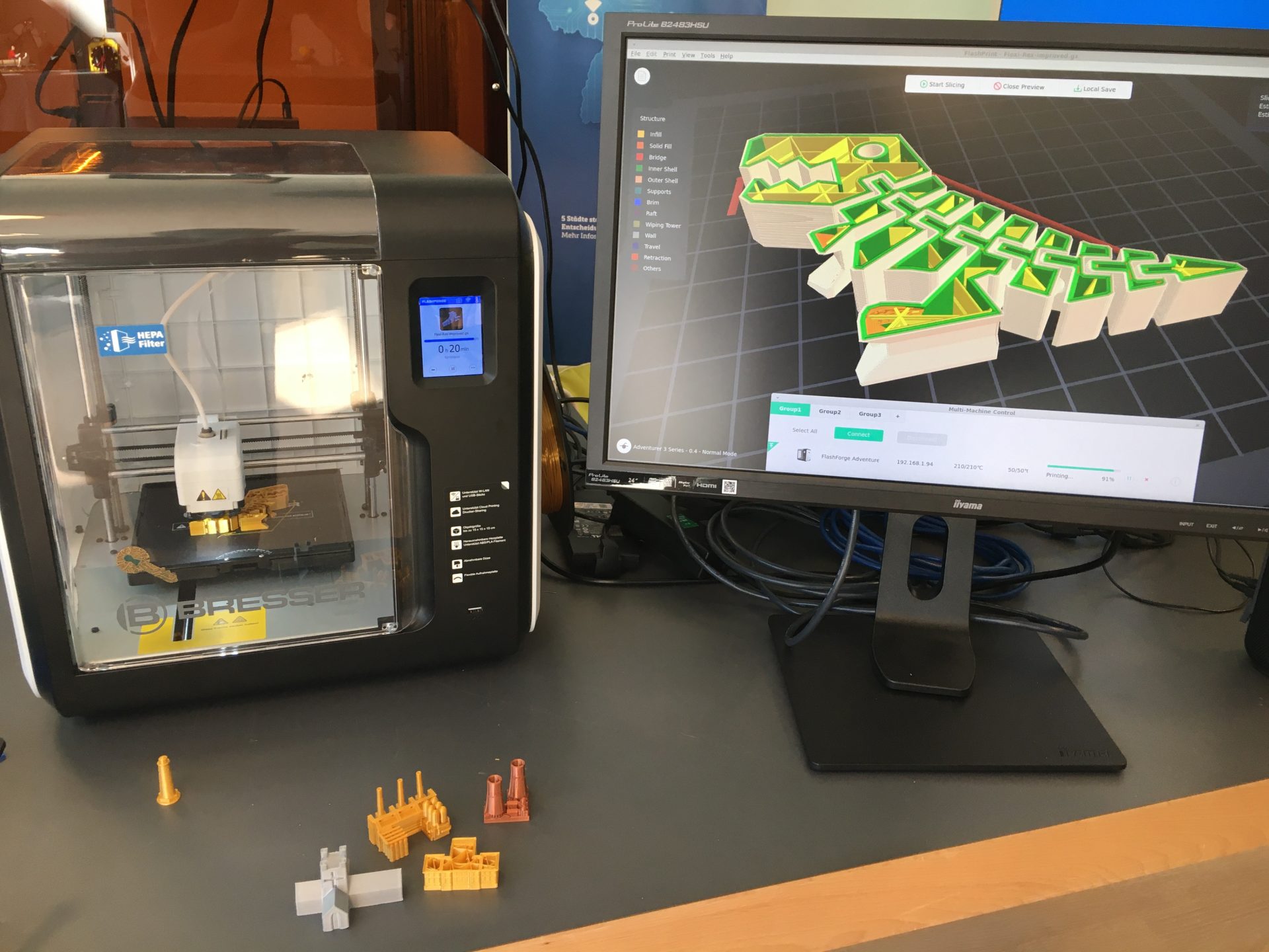 Ein kleiner 3D-Drucker neben einem Laptop, der ein designprogramm zeigt