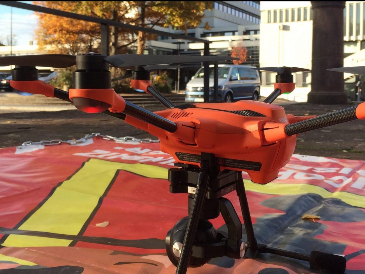 Eine orangener Multicopter steht auf einer roten Plane