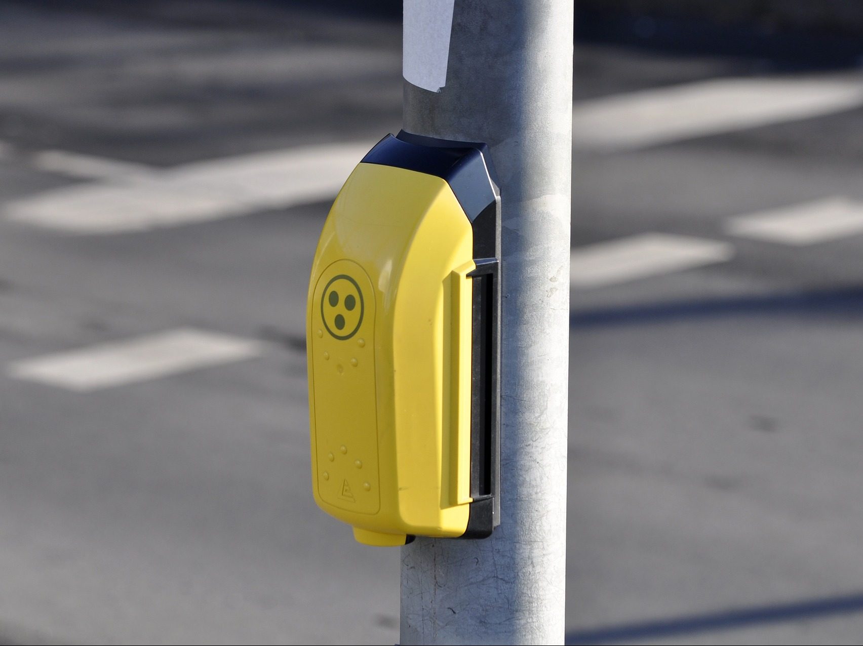 Ein gelber Ampelknopf mit dem Zeichen für Blinde