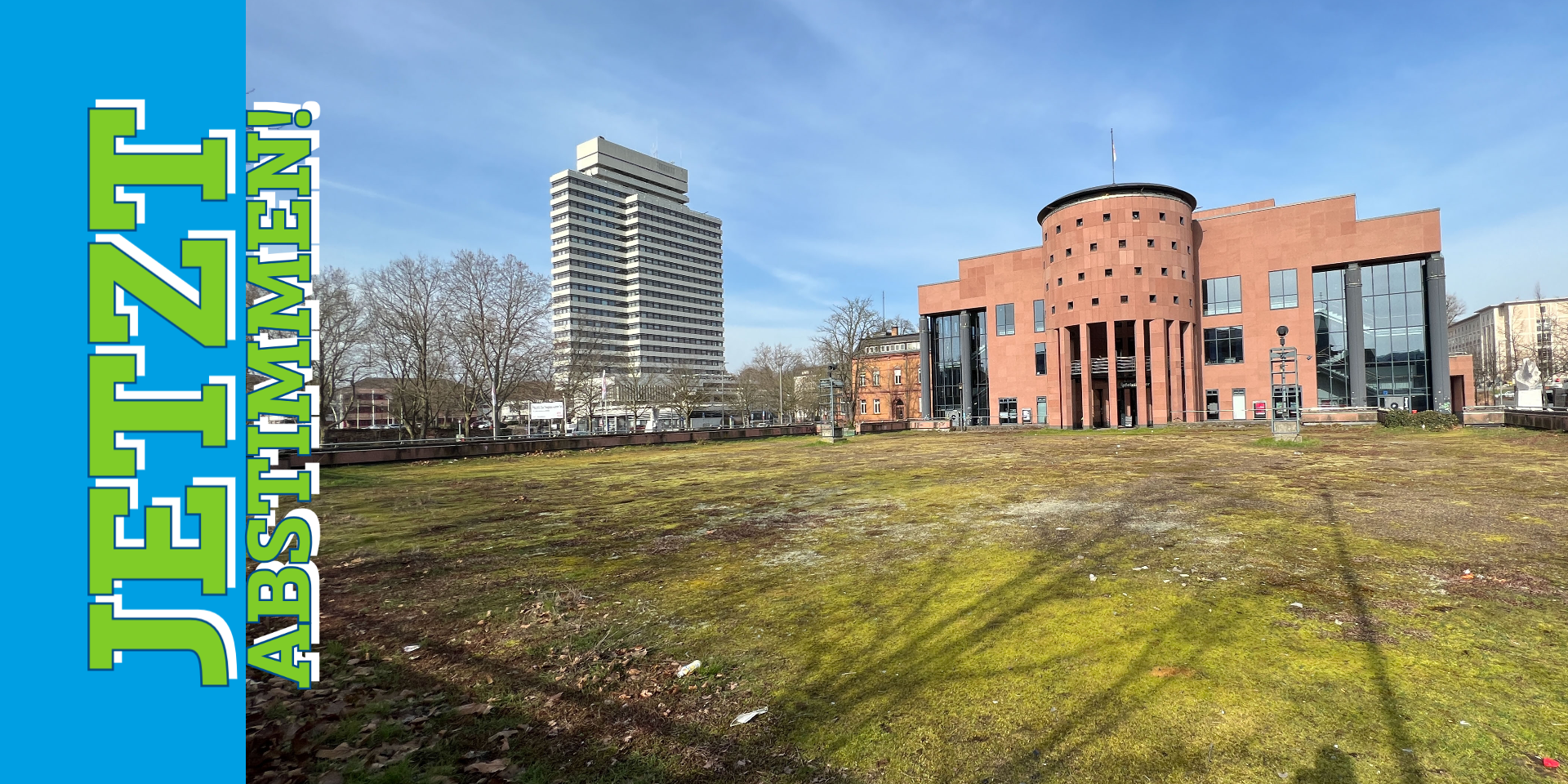 Offener Platz mit Moss auf dem Boden, dahinter ein Sandsteingebäude mit einer Rotunde (Pfalztheater Kaiserslautern) und ein Hochhaus (Rathaus Kaiserslautern)