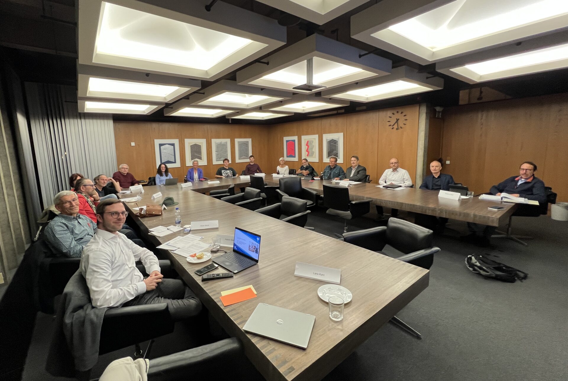 Mehrere Personen sitzen um einen Konferenztisch verteilt.